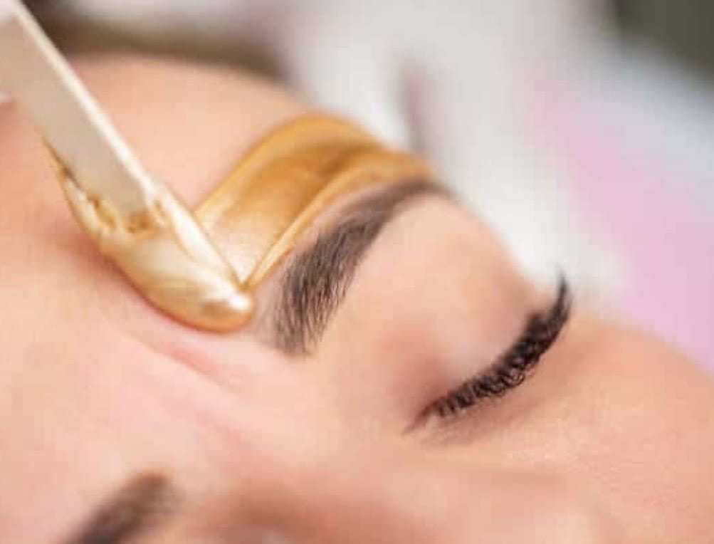Close-up of a person's eyebrow being groomed with wax for shaping.